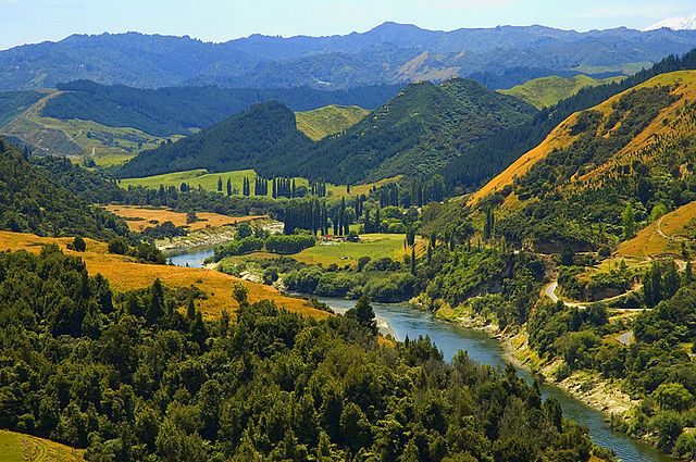 The blue-green Whanganui River winds its way through a farmland valley 