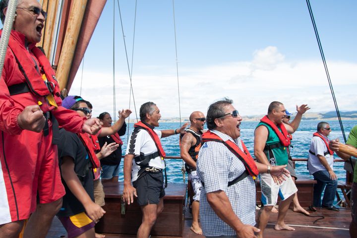 Māori men and women in life jackets perform a haka on the deck of a fishing vessel 