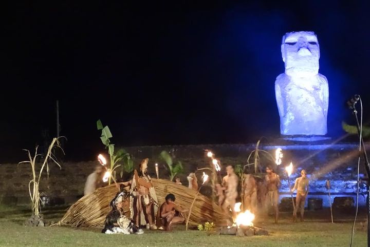 At night on a field in Rapa Nui performers in traditional dress move about, some with fire sticks